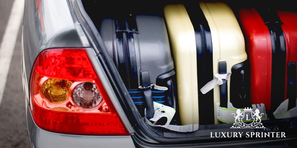 Overfilled car trunk with full suitcases on the street, showing the lack of space in a standard saloon vehicle.